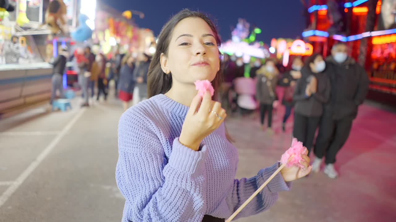 Young woman enjoying cotton candy at a night fair