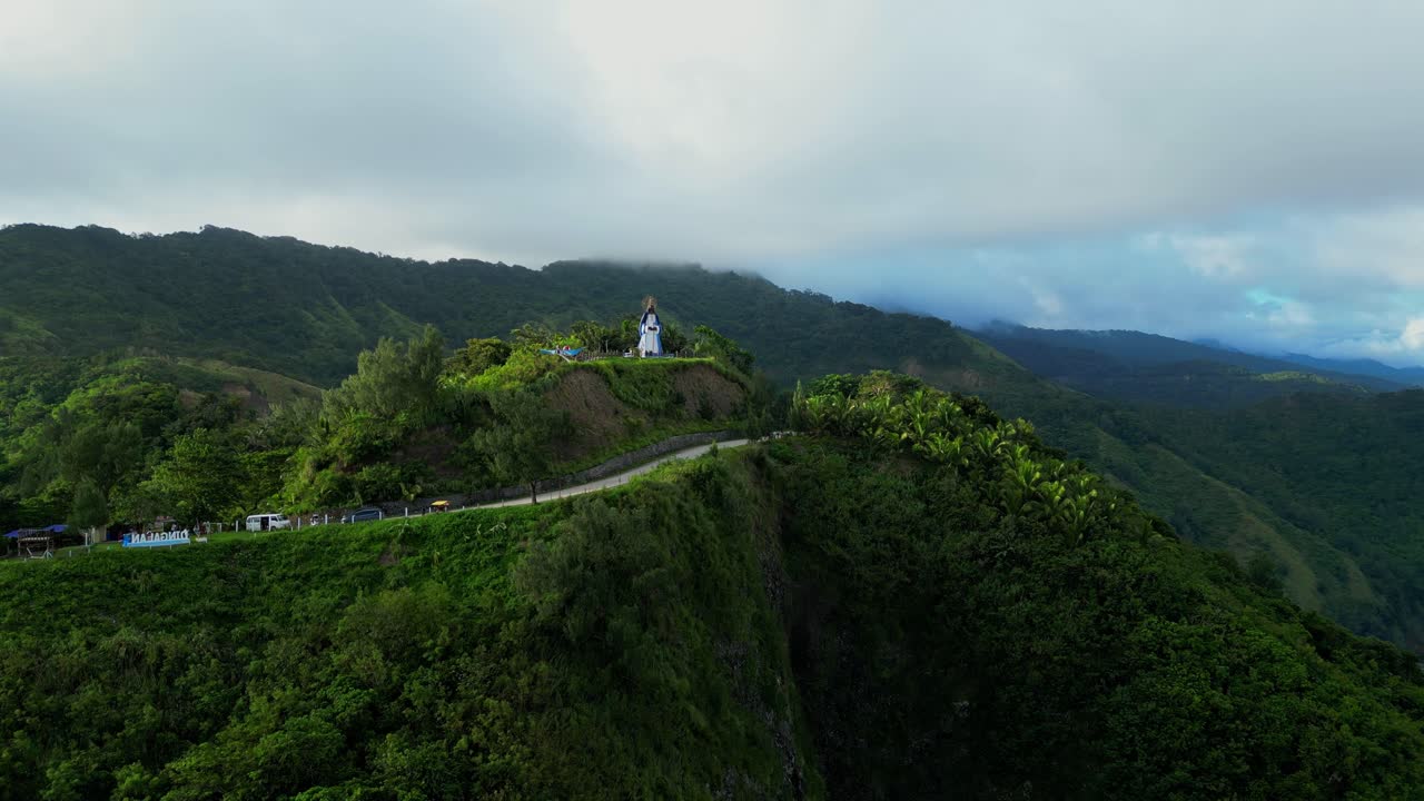 Wide aerial view of La Nuestra Señora dela Paz y Buen Viaje Statue in Dingalan, Aurora, standing atop a lush green hill overlooking the vast blue sea and distant mountains