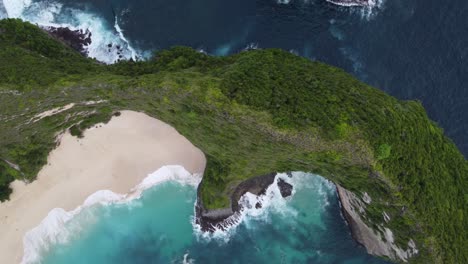 kelingking beach on nusa penida island with sandy cove down a lush steep jurassic looking rock formation