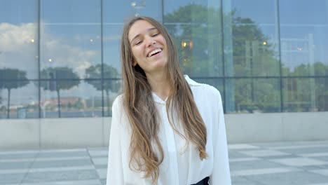 Corporate-woman-awkwardly-laughs-and-smiles-by-modern-office-building