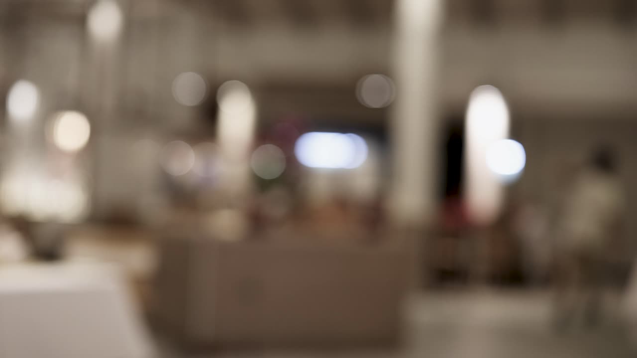A person walks through a dimly lit restaurant, captured in a series of blurred frames, creating a dynamic and mysterious atmosphere
