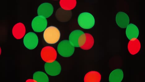 bokeh shot of defocused blurred christmas tree light that is blinking on black