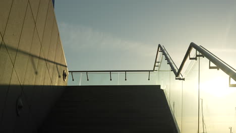 concrete staircase leading to glass balustrade against a sunlit sky with soft clouds