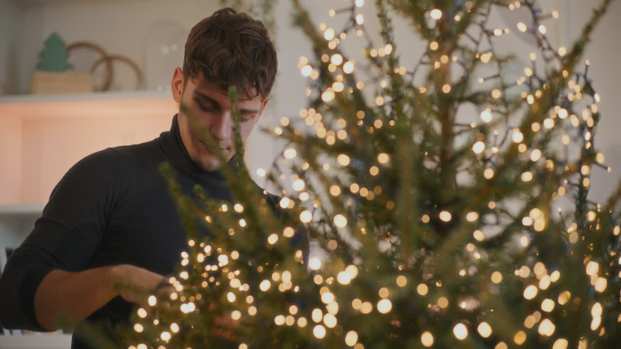 Homem com luzes LED decorando a árvore de Natal