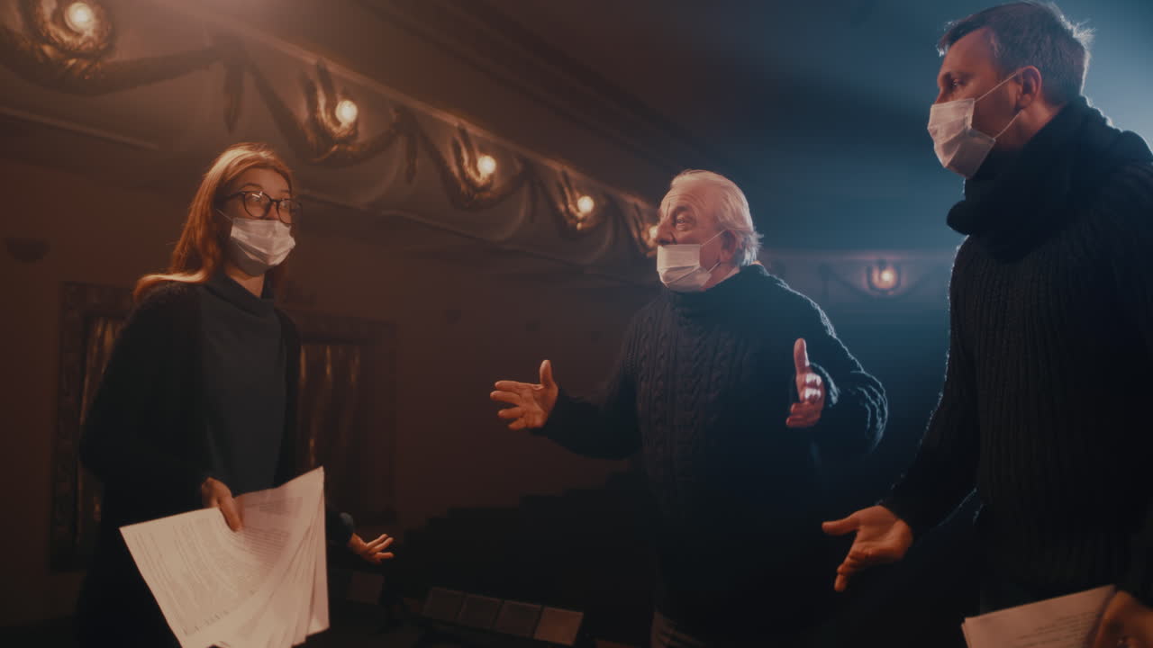 Actors in Face Masks Acting out Quarrel on Stage Actress in Mask Screaming at Adult Actor Near Agitated Senior Man then Throwing Papers and Walking Away