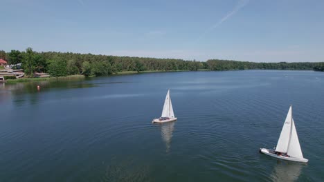 Sailboats-sail-on-a-lake,-distant-drone-parallax-shot