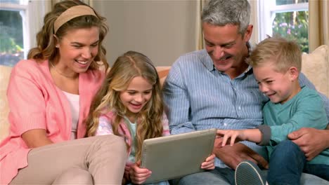 smiling family using technology on sofa