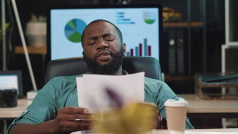 closeup tired afro business man drinking coffee in hipster office