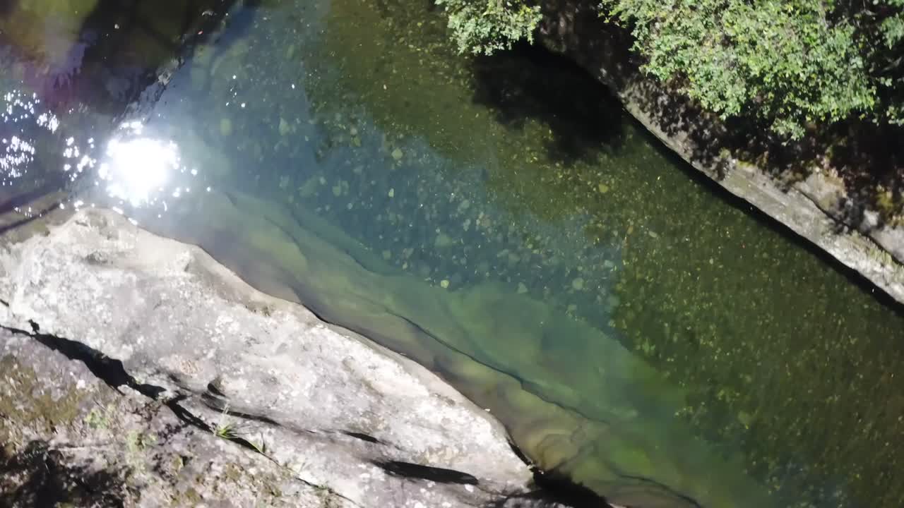 드론은 시원하고 맑은 계곡을 내려다보고 빠르게 회전하여 바닥에 있는 바위, 자갈 및 모래를 보여줍니다.