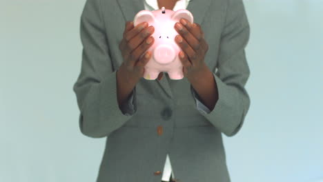 businesswoman shaking coins out of piggy bank