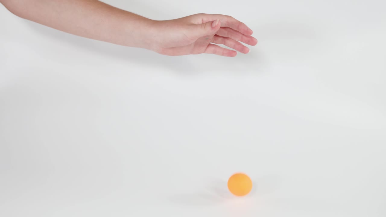 mano dejando caer una pelota de ping pong