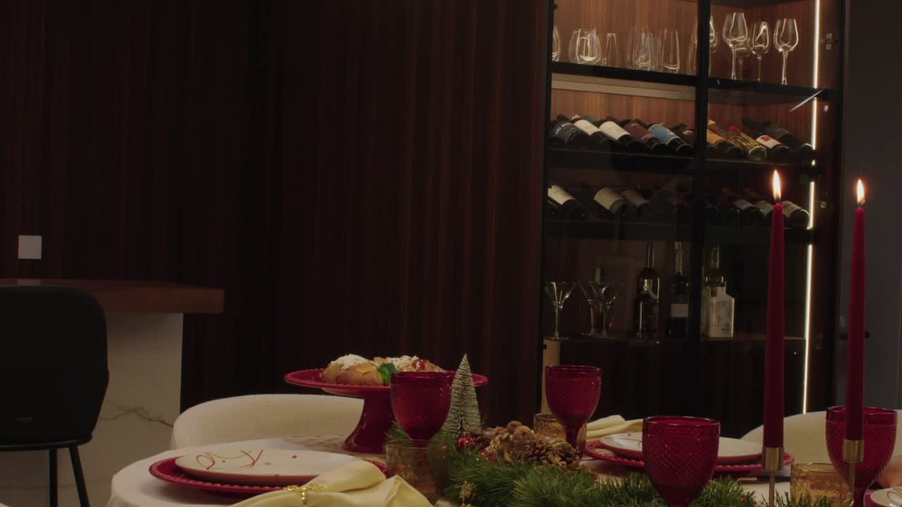 christmas dinner table with red candles red glassware and festive decor near wine display