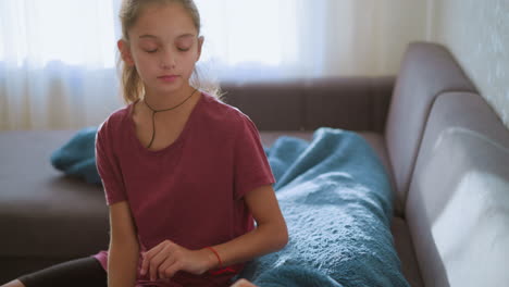 caring girl with rope on neck sits beside person covered in blanket on couch checking temperature showing concern compassion in emotional moment indoors under soft window light
