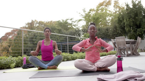 feliz hija afroamericana y madre practicando yoga en el jardín soleado, cámara lenta