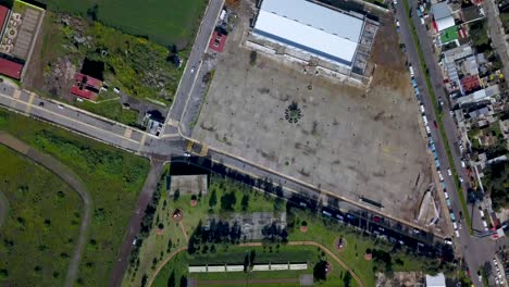 Rotation-drone-view-of-a-soccer-field-and-warehouse-in-the-charming-town-of-chalco-Mexico,-and-view-of-the-highway-town-and-houses-population-density