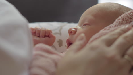 mum stroking gently sleepy newborn baby