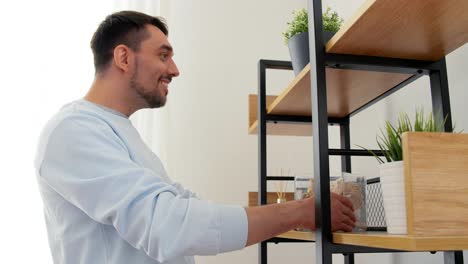 Man-Decorating-Home-with-Seashells-in-Vase.home-improvement-and-decoration-and-people-concept--woman-placing-seashells-in-vase-to-shelf