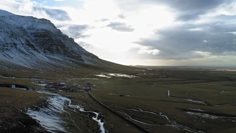 Flying-over-the-beautiful-brown-landscape-by-the-snowy-rock-mountain-,-Iceland---aerial