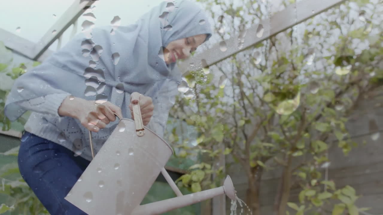 Animation de gouttes d'eau sur une femme biraciale en hijab avec un arrosoir, jardinant