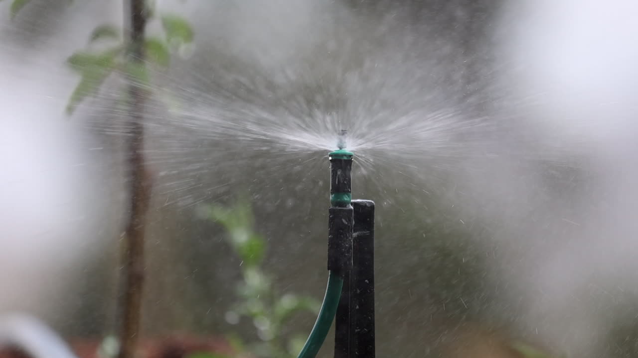 Panoramica Lenta su Irrigatore con Acqua che Spruzza Nebbia, Primo Piano