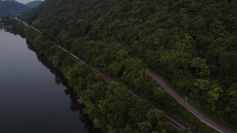drone tracking a passenger train along a riverbank
