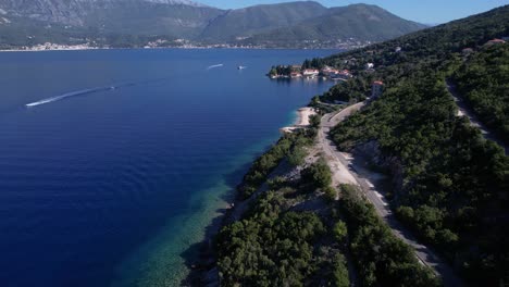 Vista-Aérea-De-La-Bahía-De-Kotor,-Mar-Adriático-Azul-Y-Pueblo-Rosa,-Montenegro,-Disparo-De-Drone