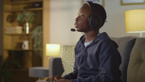 boy at home sitting on sofa wearing headset playing video game 2