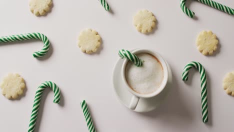 video of green christmas canes and cup of coffee over white background