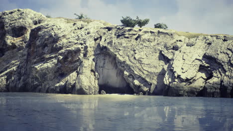 rocky shoreline with calm water and trees under a bright sky