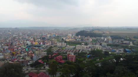 un avión no tripulado empujado por encima del bosque revela una densa ciudad nepalí con nubes por encima