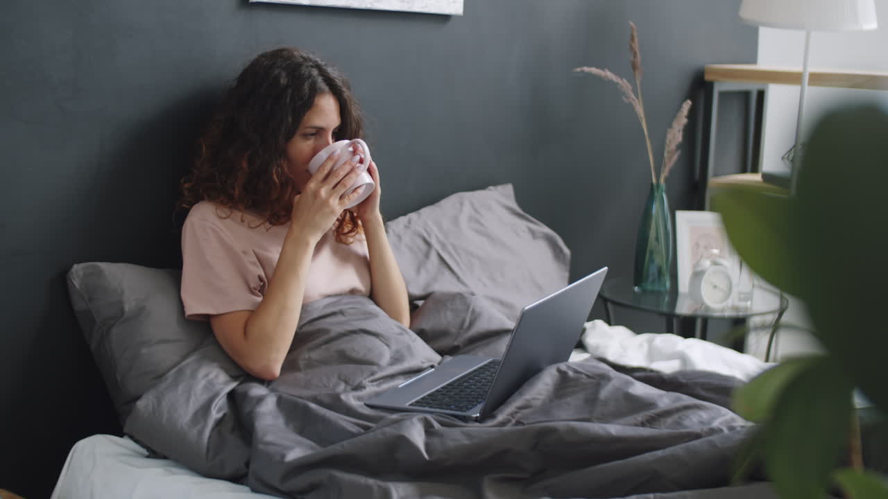 침대에 노트북으로 일하는 여자