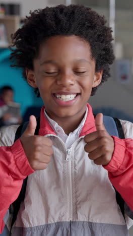 a young boy gives a thumbs up and smiles while standing in a school.