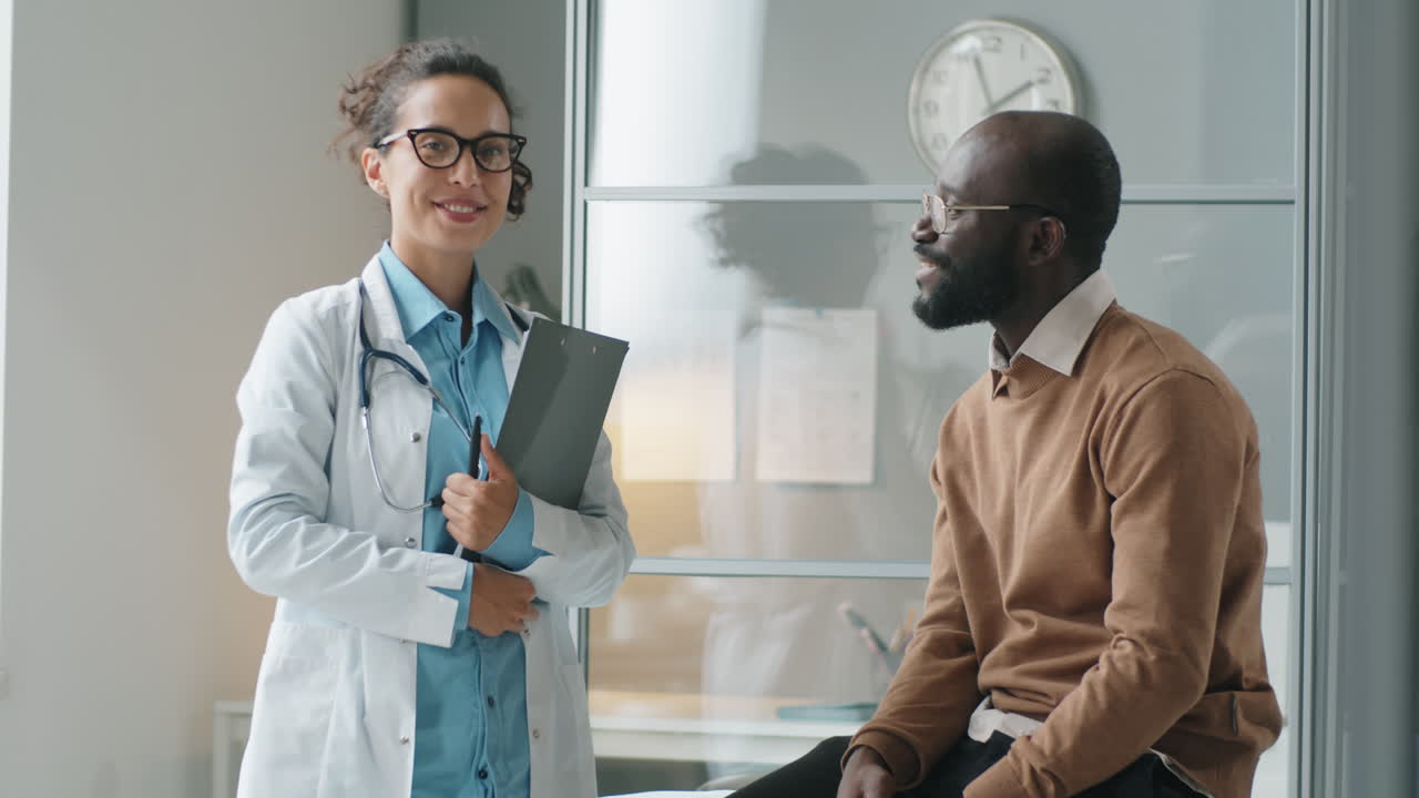 Portrait of Cheerful Female Doctor and African American Man in Clinic