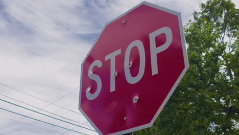 stop sign riddled with bullet holes, welcome to our town, stop violence