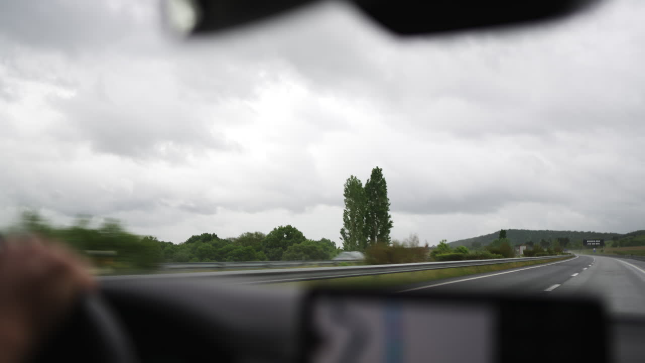 POV: Guidando su un'autostrada bagnata con tempo nuvoloso.