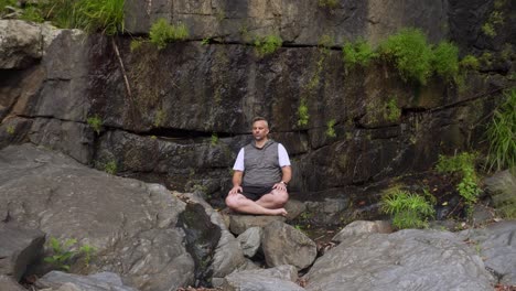 man meditating on rocks in nature