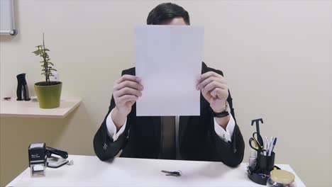 hombre de negocios escondiendo la cara detrás del papel
