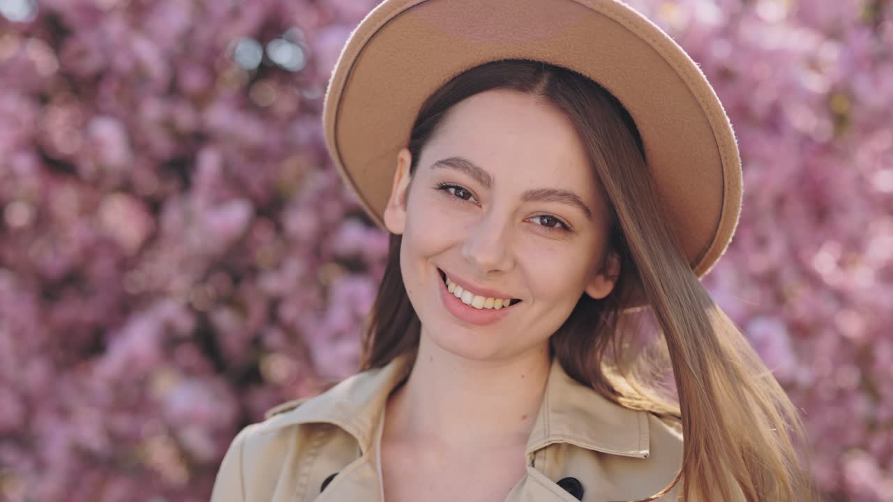 Woman in a hat, smiling in a spring park