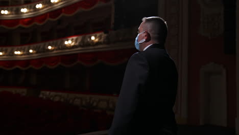 man entertainer, presenter or actor on stage. active gestures of clapping to the auditorium. view of a male public speaker speaking at the microphone.