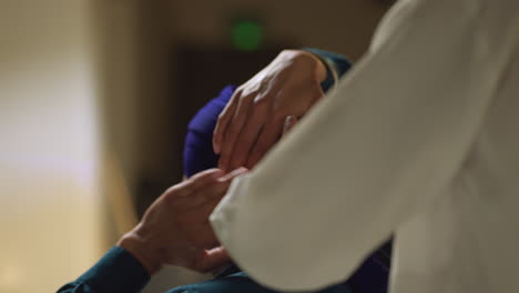 close up studio shot of senior sikh man helping younger sikh man to tie fabric for turban against plain background shot in real time