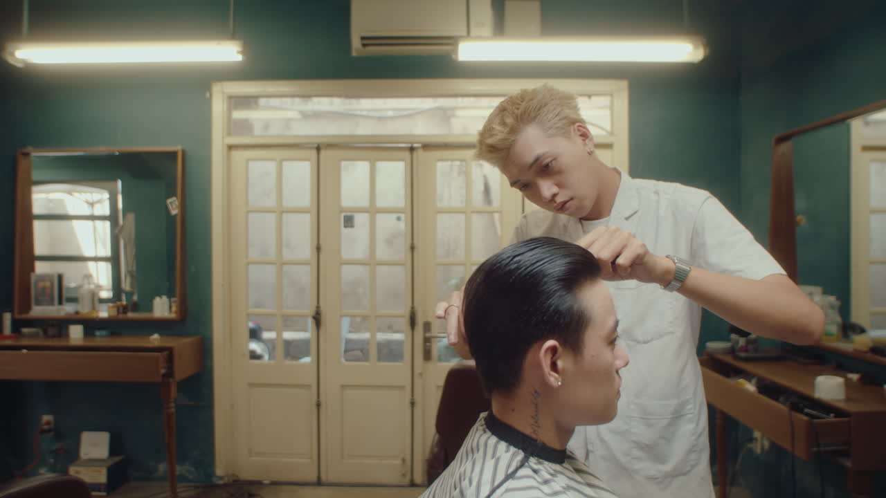 Asian Barber Trimming Hair of Client in Hairdressing Salon