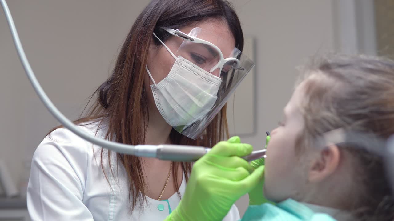 Dentist cleans girl's teeth with professional toothpaste. Girl with white teeth at the dentist's office. Shot in 4k