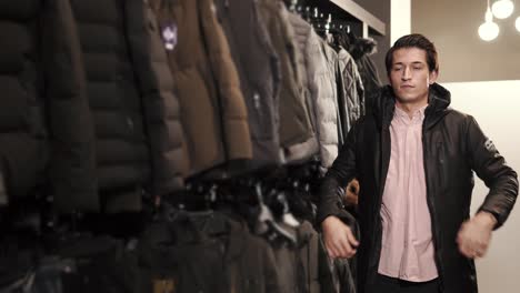 a young man chooses a jacket in a clothing store, he tries on a sample for himself