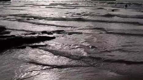 cornish uk coast in summer. bright sun reflecting glaringly in ocean waters, tide is in. people swimming, boy falls in water, while coming back to a shore; sun will start setting soon. footage in hd
