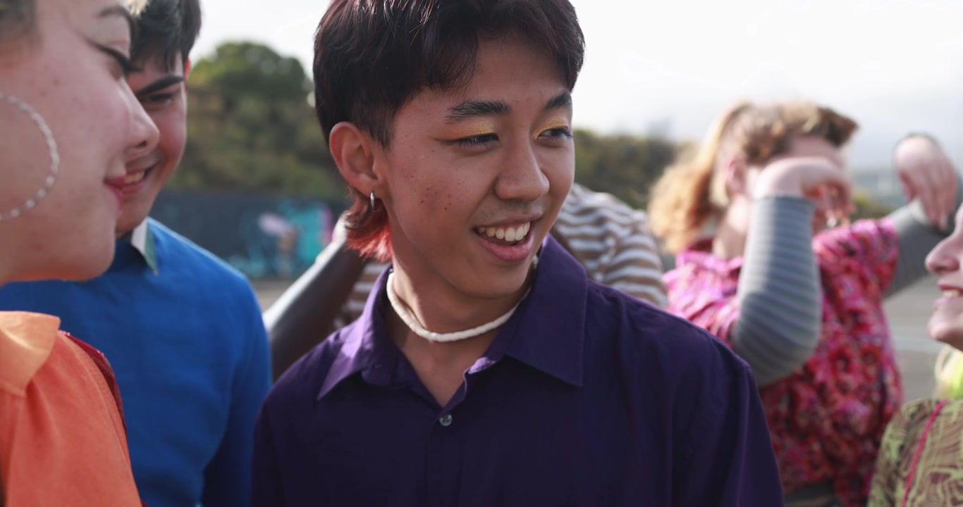 屋外で笑顔と笑い声が響く、多様な若い友人グループ。