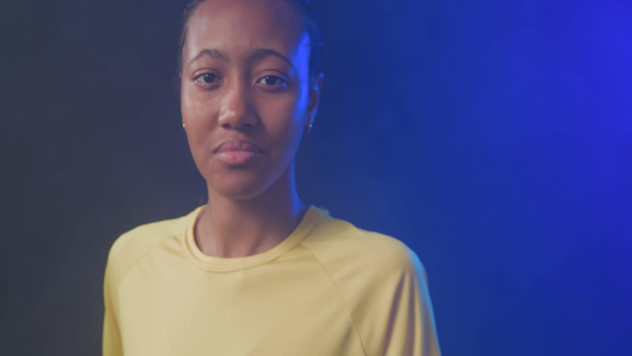 Donna afroamericana che tiene un pallone da calcio con un guanto, mentre la telecamera si allontana mostrando una luce blu.