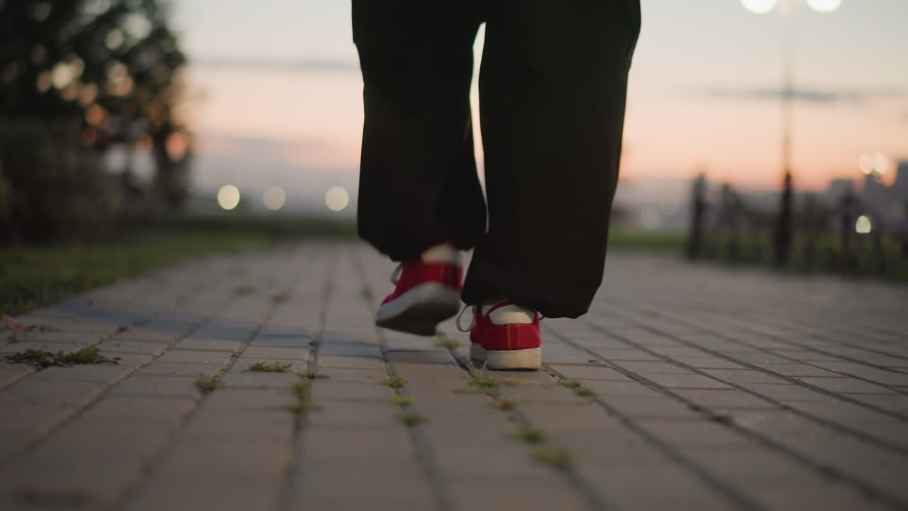 sunset street dancer practicing footwork, closeup red sneakers on tiled pavement, slow intimate steps, lamppost bokeh, evening skyline, calm cinematic mood, focused rehearsal sequence