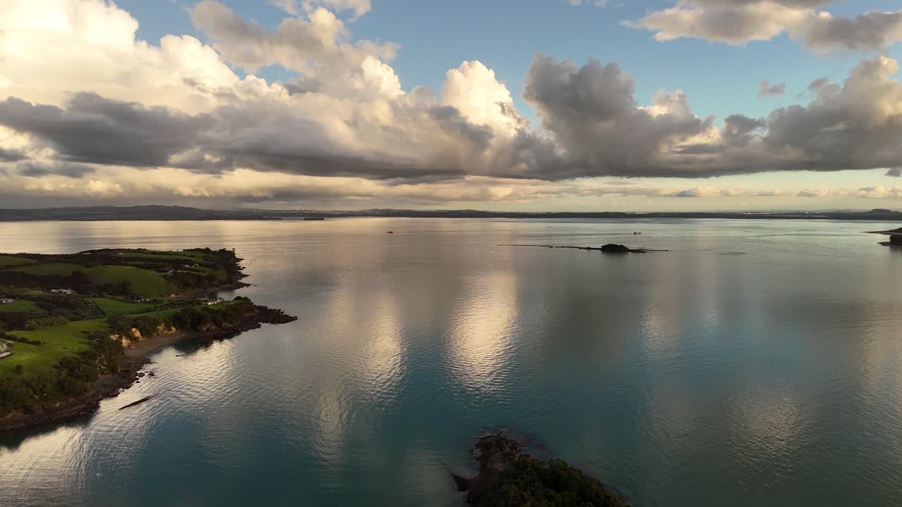 Stunning view of tranquil sea waters reflecting soft golden light beneath a cloudy sunset sky. The calm surface and dramatic sky create a peaceful, contemplative scene