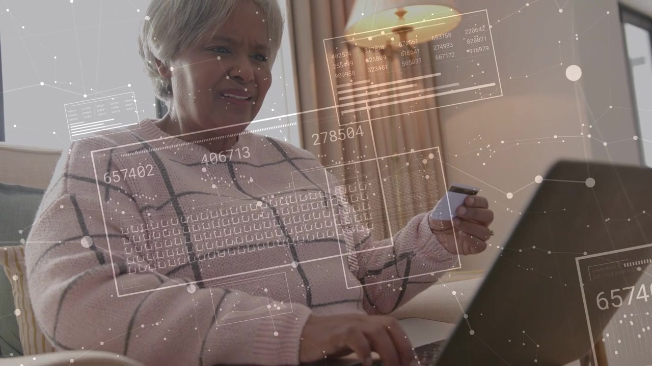 Donna anziana che inserisce un pagamento sul laptop in poltrona, tenendo una carta, con sovrapposizioni finanziarie che mostrano numeri