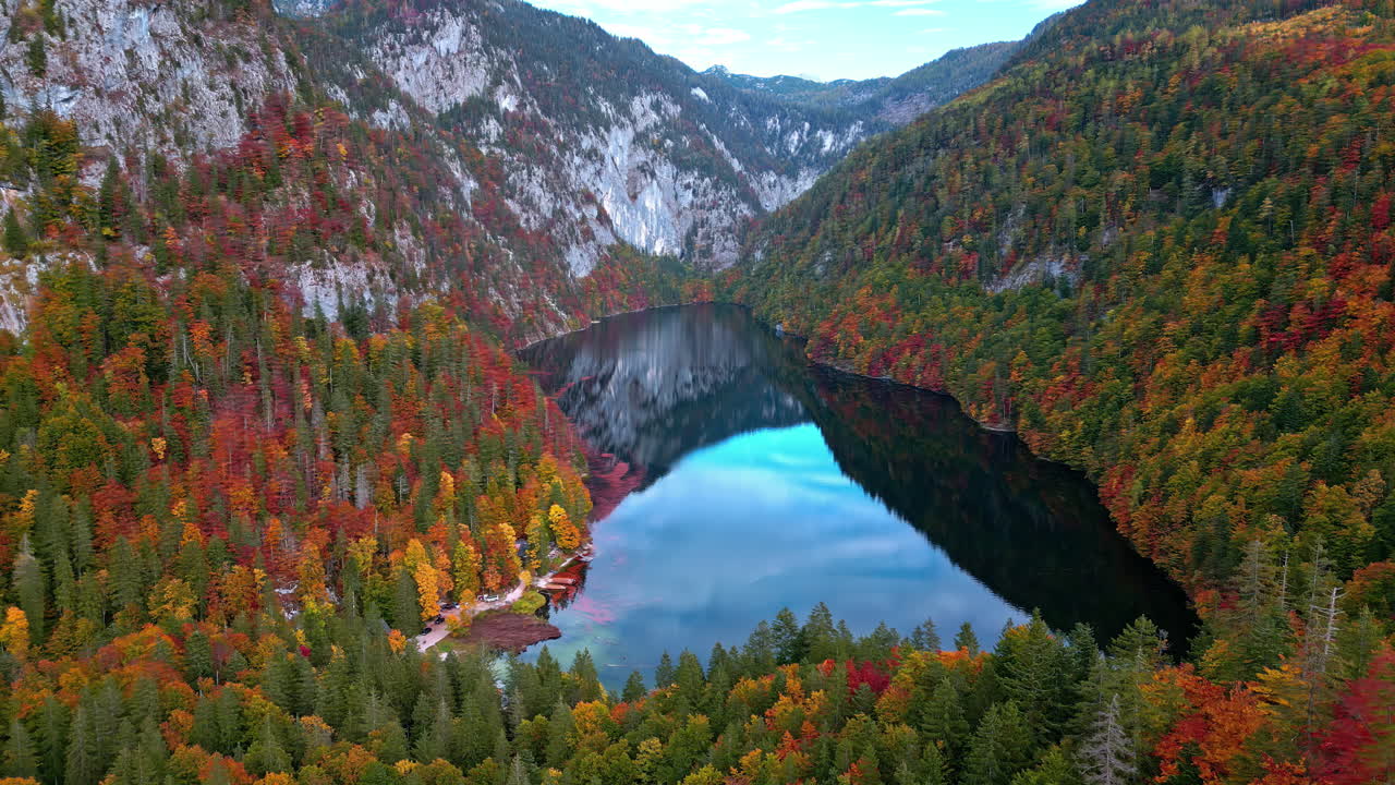 Acqua calma con foresta autunnale rosso-arancio nel lago Toplitz, Austria.